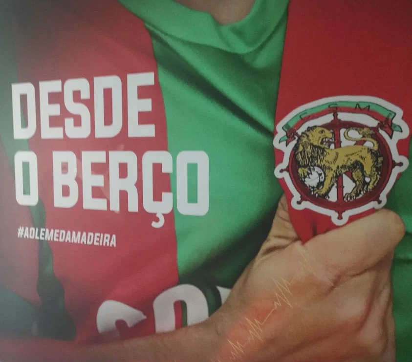 Camiseta oficial do CS Marítimo nas cores verde e vermelha com o brasão do clube e a frase Desde o Berço - #AolémDaMadeira